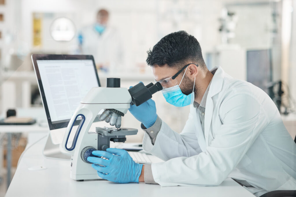 Pathologist reviewing specimens under a microscope as part of a data-driven pathology workflow